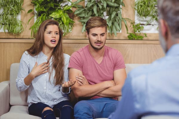 A couple speaking with a counsellor during a therapy session, expressing concern and frustration.