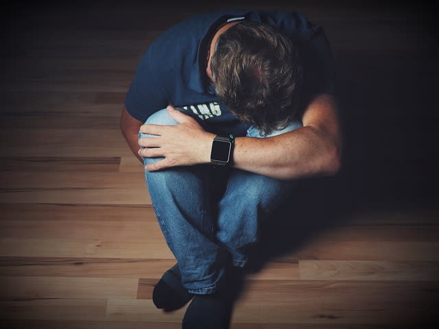 depressed man sitting on the floor with head in knees