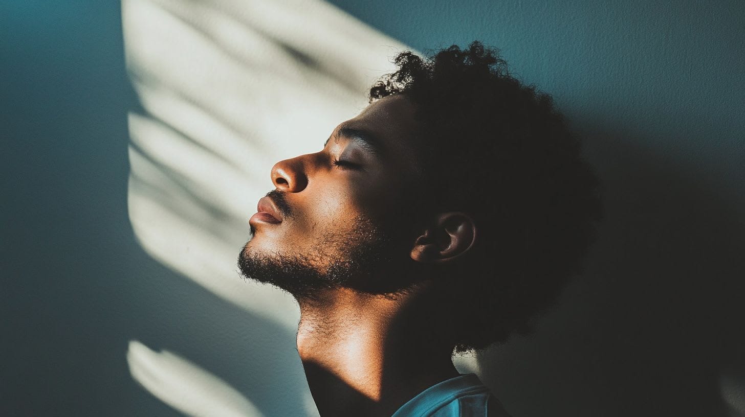 A man looking towards light with closed eyes